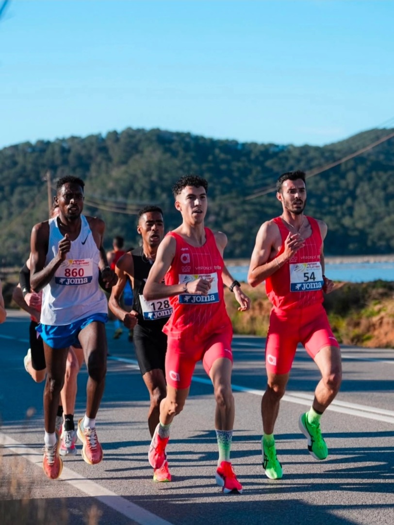 Un grupo de atletas compite en plena carrera durante el Campeonato de España de 10 km en Ibiza, con Santiago Catrofe ubicado entre los protagonistas en un tramo del recorrido sobre carretera, rodeado de paisaje natural y bajo cielo despejado.